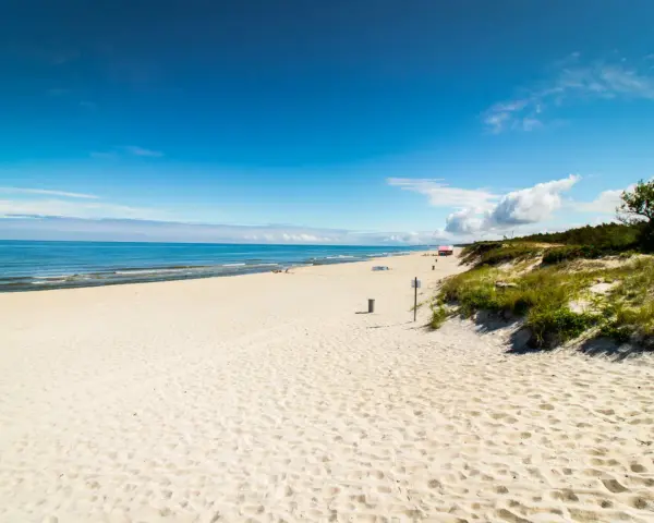 Piękna, piaszczysta plaża na Mierzei Wiślanej. Błękitne niebo i spokojne morze zapraszają do wypoczynku.