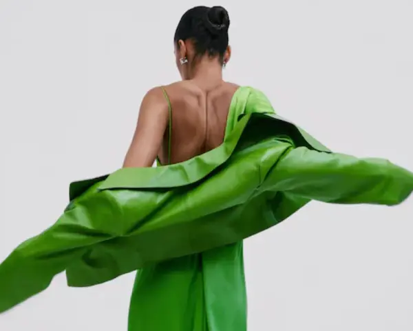 Mujer con un vestido verde brillante y una chaqueta verde vibrante. Un look audaz para combinar vestido verde con chaqueta.