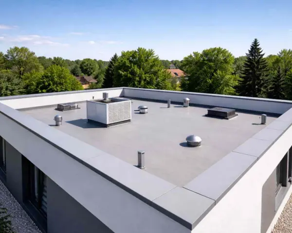 Nowoczesny dach płaski bez attyki z systemem wentylacji i klimatyzacji, otoczony zielenią.