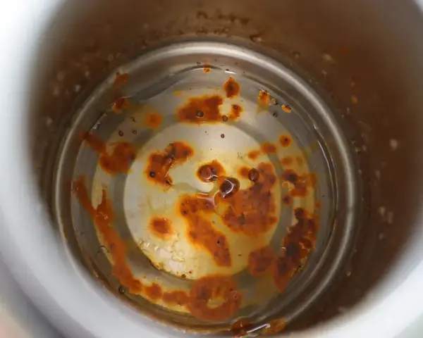 Intoxication eau gourde : intérieur rouillé d'une gourde, avec des dépôts orangés et de l'eau trouble.