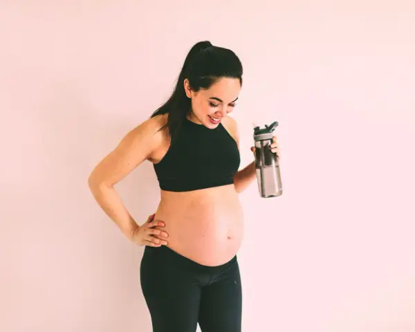 Aktywna przyszła mama z butelką wody, dbająca o zdrowie i poziom cukru. Insulina w ciąży pod kontrolą dzięki zdrowemu stylowi życia.