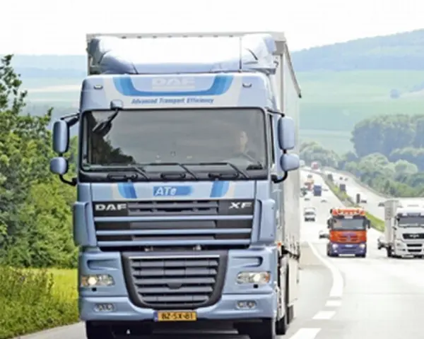 Niebieska ciężarówka DAF XF 105 na autostradzie, otoczona zielenią. W tle inne pojazdy i pagórkowaty krajobraz.