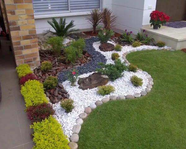 Piccoli giardini da sogno con ghiaia bianca, pietre scure, piante verdi e fiori rossi, un'oasi di pace.