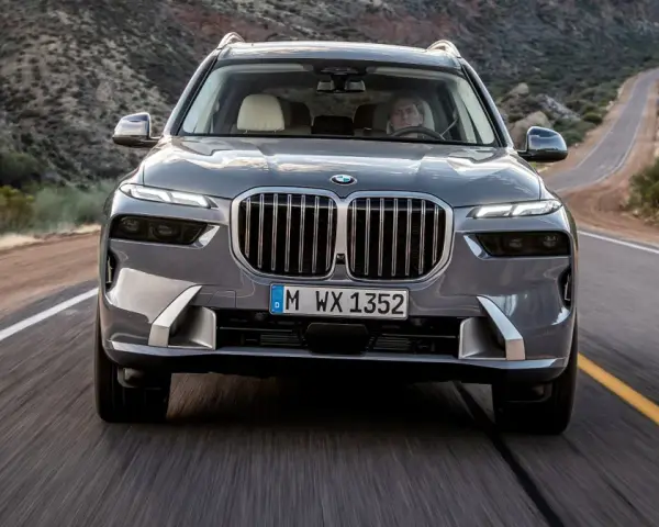 Szary BMW X7M pędzi krętą drogą przez pustynny krajobraz.