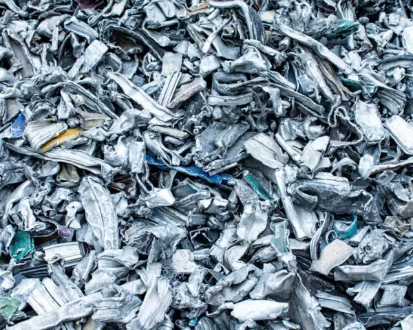 Góra poskręcanego, poszarpanego złomu metalowego, gotowego do recyklingu metalu. Widać fragmenty niebieskiego i żółtego plastiku.