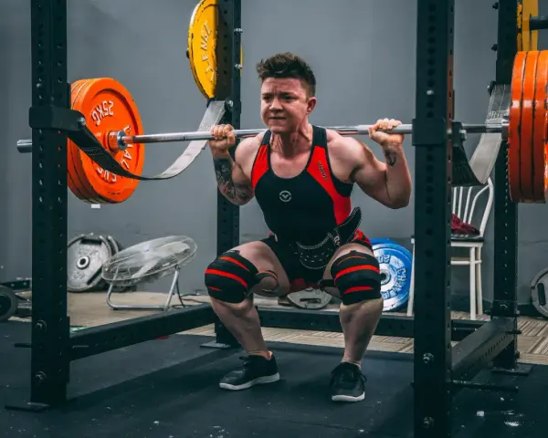 En person utför squats med vikt i ett gym.