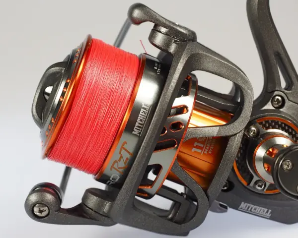 Nahaufnahme einer Mitchell Angelrolle mit leuchtend oranger Schnur, bereit für den perfekten angelrollen knoten.