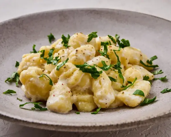 Pyszne gnocchi z kremowym sosem, posypane świeżą natką pietruszki. Idealne danie dla każdego miłośnika włoskiej kuchni.