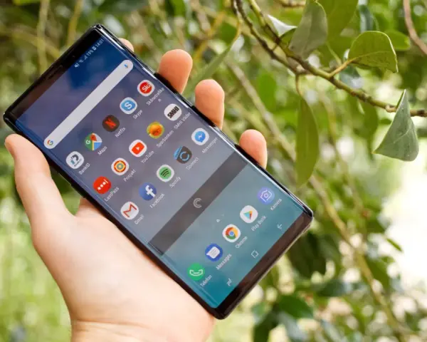 En hand håller en Samsung Galaxy Note 9 med många appar på skärmen, bland annat BankID och Spotify.