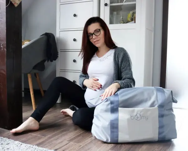Gotowa na poród! Ciężarna kobieta z torbą, czyli wyprawka do szpitala czeka.