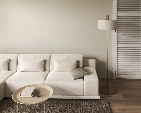 Divano modulare color tortora, tavolino ovale con libri, lampada da terra dorata e porta a soffietto in legno.
