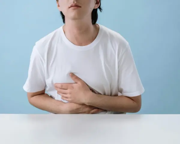 Persona con le mani sull'addome, che esprime disagio per nausea e giramenti di testa dopo allenamento.