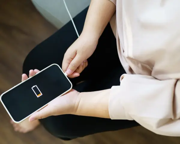 En person kopplar in sin iPhone som drar mycket batteri. Batteriikonen visar låg laddning.