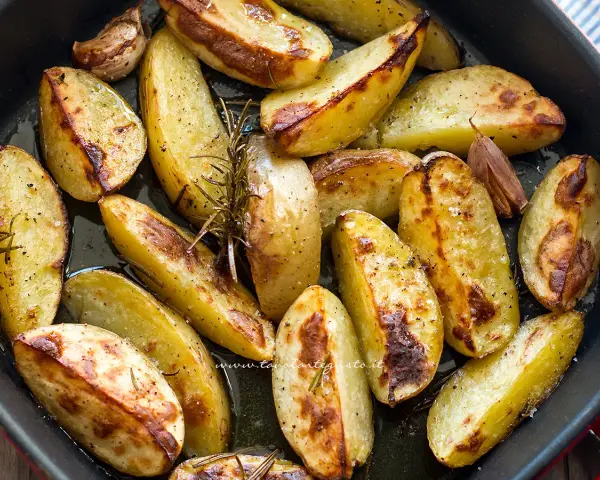 Patate al forno croccanti, dorate e profumate al rosmarino e aglio, pronte per essere gustate.