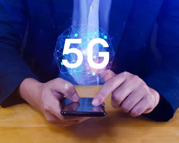 Dłoń na smartfonie, symbol 5G nad nim. Dowiedz się, jak wyłączyć 5G w telefonie, aby kontrolować połączenie.