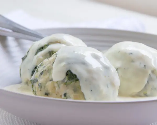 Drei Klöße mit Spinat, übergossen mit einer cremigen Gorgonzolasauce. Ein italienisches Original-Rezept für Genießer.