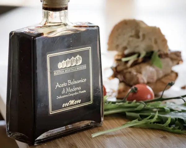Butelka octu balsamicznego z Modeny obok kanapki i rukoli. Czy ocet balsamiczny jest zdrowy?