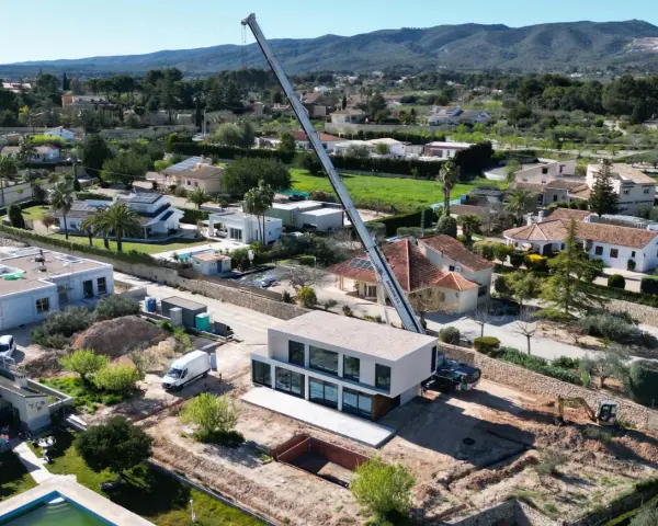 Construcción moderna en zona residencial, mostrando la diferencia entre urbano y urbanizable con grúa y excavadora.