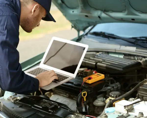 Mechanik diagnozuje usterkę w Oplu p2279, używając laptopa i multimetru.