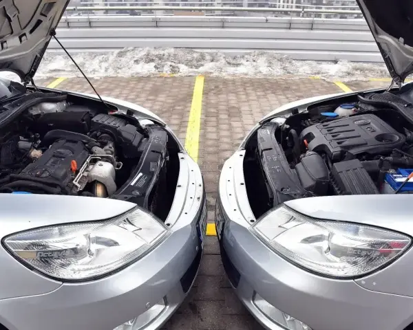 Dwa silniki samochodowe, jeden z napisem TDI (diesel), drugi bez widocznego oznaczenia, stoją obok siebie. Dylemat: diesel czy benzyna?