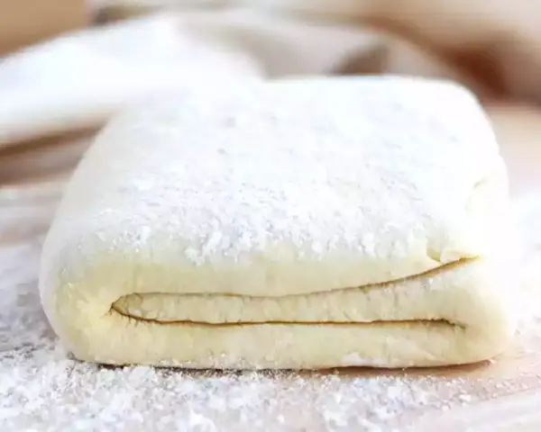 Gotowe ciasto francuskie, idealne do nauki, jak zrobić ciasto francuskie. Warstwy ciasta posypane mąką.