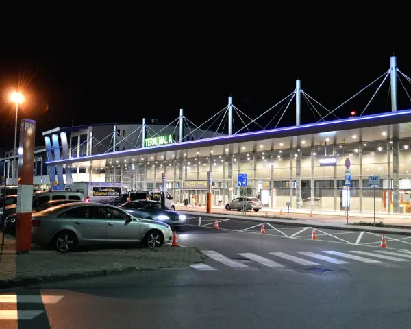 Nocne lotnisko Kraków-Balice, Terminal A. Samochody czekają na pasażerów, a światła tworzą niepowtarzalny klimat.