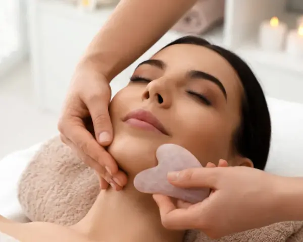 Relaksacyjny masaż twarzy kamieniem gua sha. Delikatne ruchy kamienia poprawiają krążenie i odmładzają skórę.
