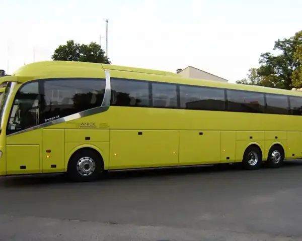 Żółty autokar firmy ANICK stoi na ulicy. Trudno określić, ile miejsc ma autokar, ale wygląda na bardzo pojemny.