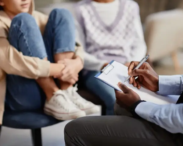 Un professionnel note des informations sur un jeune en difficulté, peut-être pour savoir comment faire une information préoccupante.