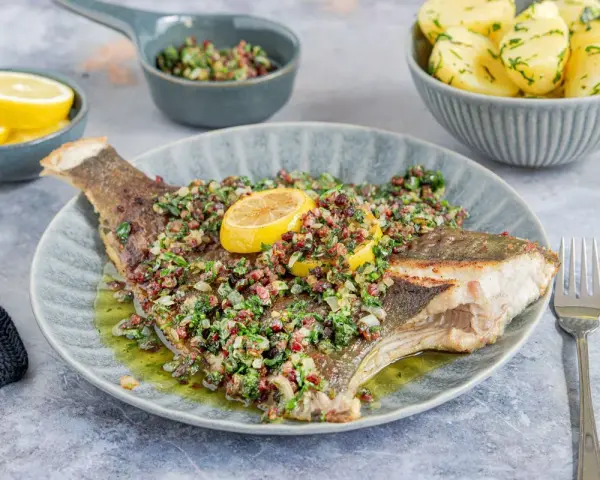 Gebratene Scholle mit Kräutern und Zitrone, serviert mit Salzkartoffeln. Ein köstlicher Fisch für Genießer.