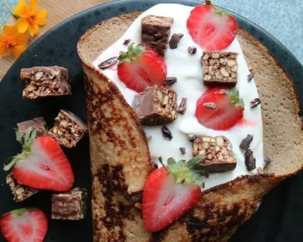 En vikad pannkaka fylld med yoghurt, jordgubbar och chokladbitar. En härlig frukost med nyttiga pannkakor som bas.