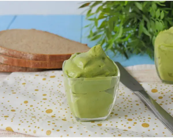 Deliziosa maionese di avocado in una ciotola di vetro, pronta per essere spalmata su fette di pane integrale.
