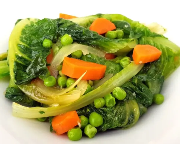 Un assortiment coloré de légumes verts feuillus, de pois et de carottes en dés, rappelant une jardinière de légumes fraîchement préparée.