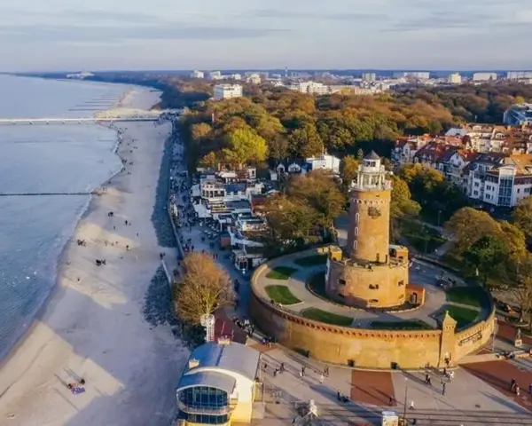 Widok z lotu ptaka na latarnię morską w Darłowie, plażę i nadmorskie miasteczko.