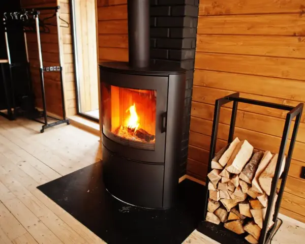 Estufas de leña canalizables modernas con fuego encendido y leña apilada, creando un ambiente acogedor en una cabaña de madera.
