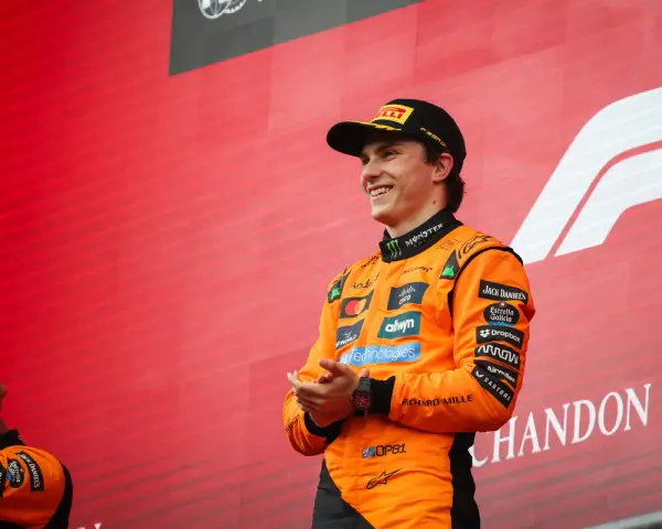 El piloto australiano F1, Oscar Piastri, sonríe en el podio con su mono naranja de McLaren.