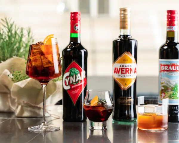 Verschiedene Campari-Sorten: Cynar, Averna und Braulio, serviert in Gläsern mit Eis und Orangenscheiben.
