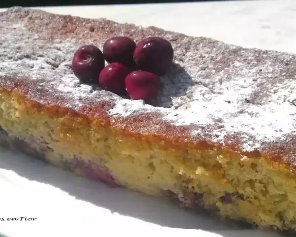 Bizcocho de cerezas casero, espolvoreado con azúcar glas y decorado con cerezas frescas.