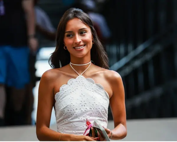 La presunta **Charles Leclerc fidanzata**, Charlotte Siné, sorride con un top bianco ricamato.