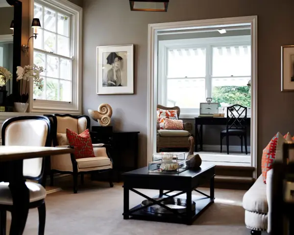 Elegante salón con paredes color topo oscuro, muebles clásicos y obras de arte.