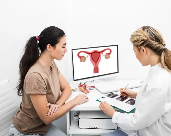 Lekarka wyjaśnia pacjentce, co to jest endometrium, pokazując schemat narządów rodnych na monitorze.