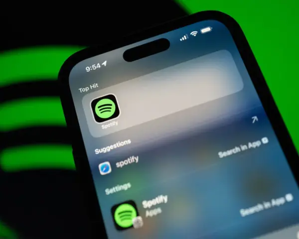 Telefon z aplikacją Spotify, sugerującą muzykę w jakości **spotify lossless**. Zielone logo Spotify w tle.