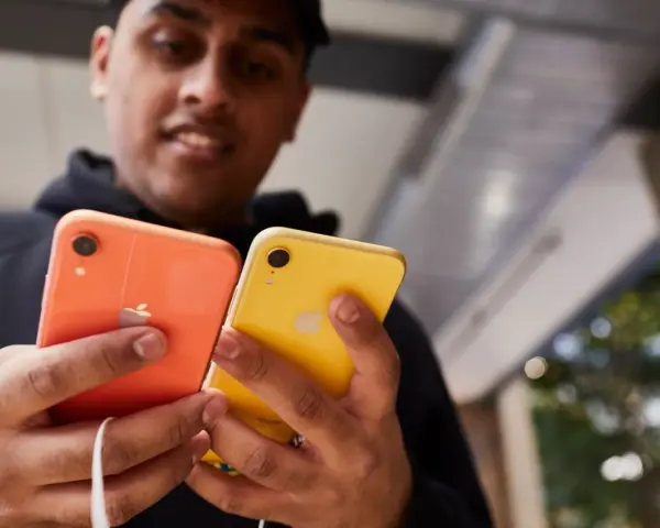 Mężczyzna trzyma dwa telefony: pomarańczowy i **iphone xr żółty**.