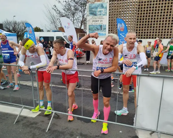 Marcin Konieczny i inni biegacze w biało-czerwonych strojach czekają na start.