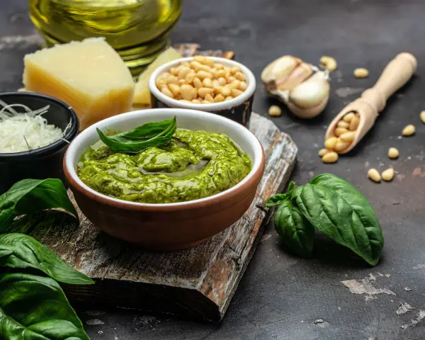 Un tazón de pesto genovés fresco con albahaca, piñones, ajo, queso parmesano y aceite de oliva.