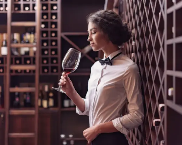 Elegancka sommelierka w piwnicy z winami ocenia aromat czerwonego wina.
