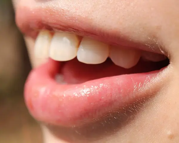 Uśmiech z białymi zębami, usta lekko rozchylone, jakby właśnie użyto nić dentystyczną do ich oczyszczenia.