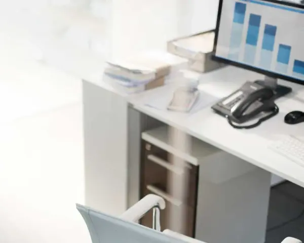 Escritorio con ordenador mostrando gráficos de barras, teléfono, ratón y teclado. La contabilidad y la variacion existencias son clave para analizar estos datos.