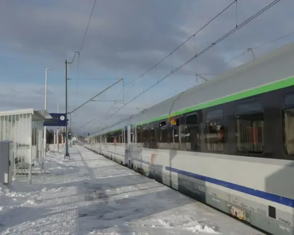 Zimowy peron 2, śnieg i pociąg do Krakowa czekają na pasażerów.