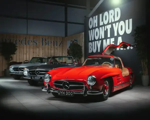 Czerwony Mercedes 300 z drzwiami skrzydłowymi, obok srebrny i szary model.